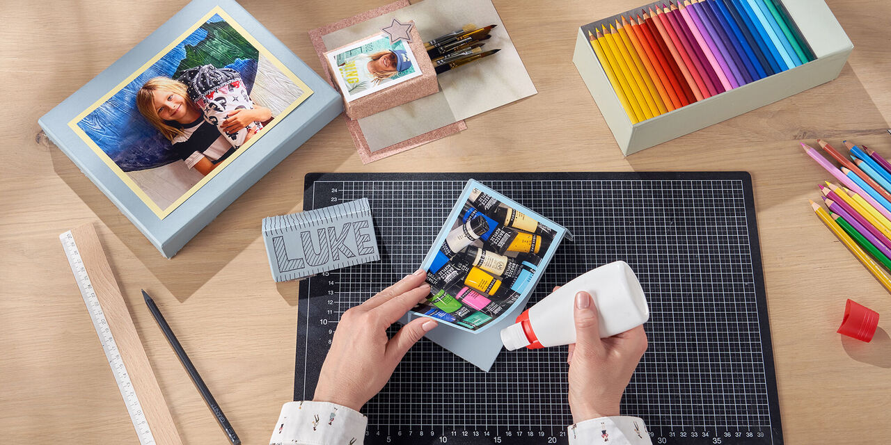 Ruke lijepe fotografiju koja prikazuje tube boje na komad kartona. Na stolu su razne kreacije.